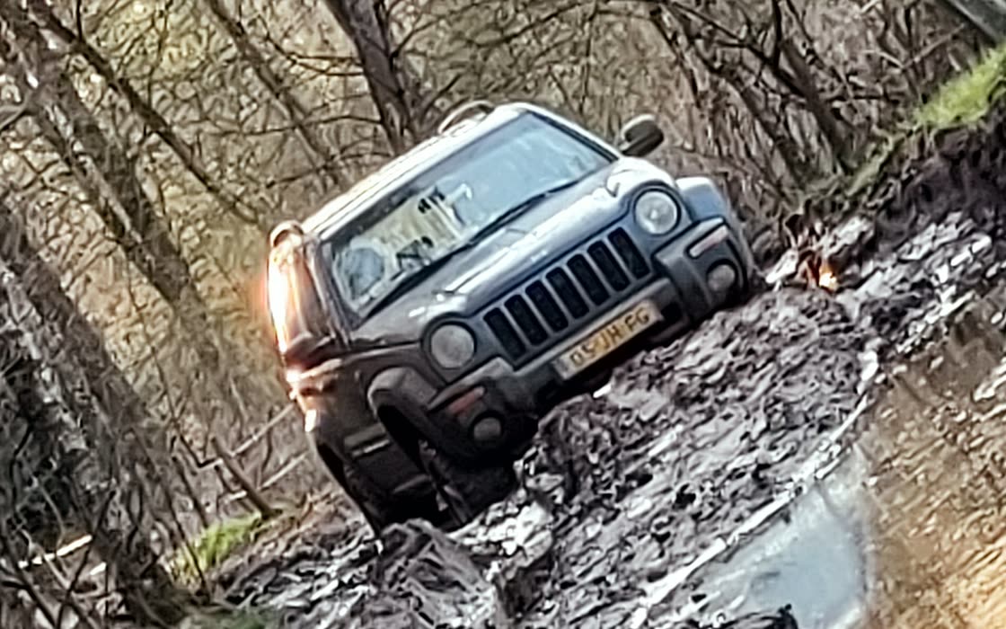Hermans Jeep Cherokee door de blubber op een bospad